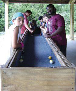 Travon Lewis, right, with Camp Mennoscah campers and a game of carpet ball.