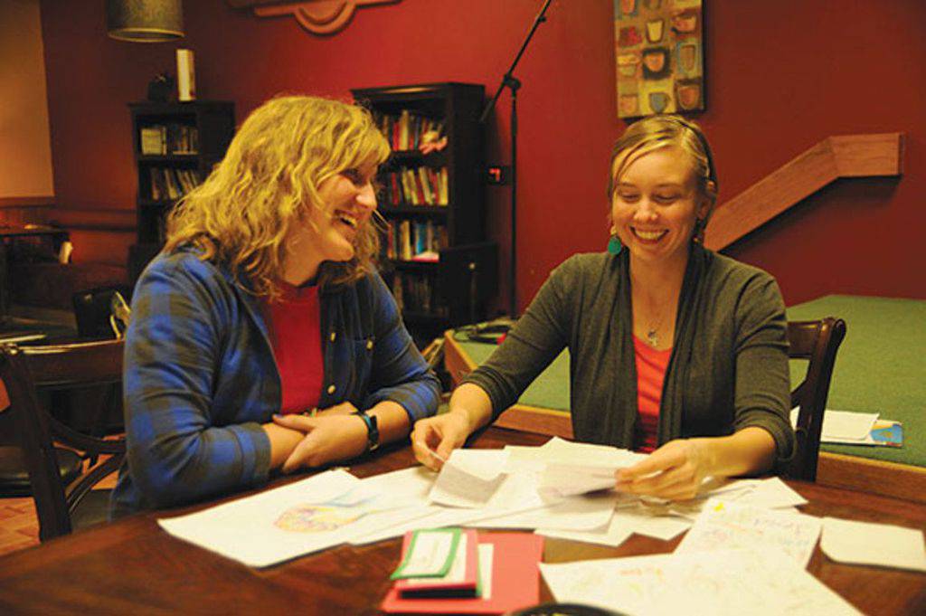 Alli Rudeen, left, and Katelyn Melgren look at some of the prayers and drawings that Bethel students left in the Campus Ministries house after 24 consecutive hours of prayer, Nov. 9–10. Rudeen and Melgren are student chaplains at Bethel who planned and organized the prayer time. Photo By Audra Miller