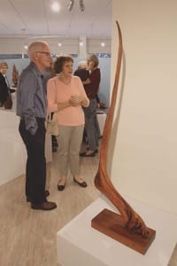 Guests enjoy John Gaeddert’s sculpture exhibition at its opening on Sept. 30; the piece pictured is “Inspiration,” bristlecone pine, courtesy of Sam ’10 and Keila ’11 Gaeddert;