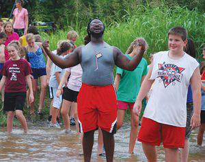 Travon Lewis, center, leads campers into the Ninnescah River.